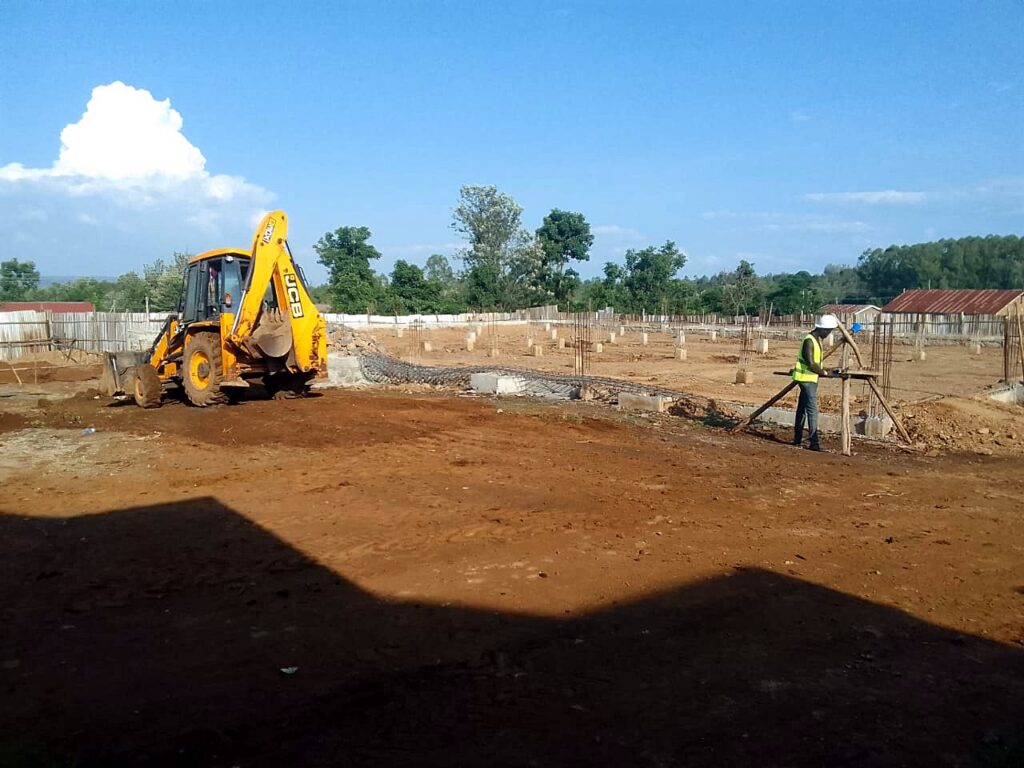 Backhoe loader and surveyor setting out on a cleared site
