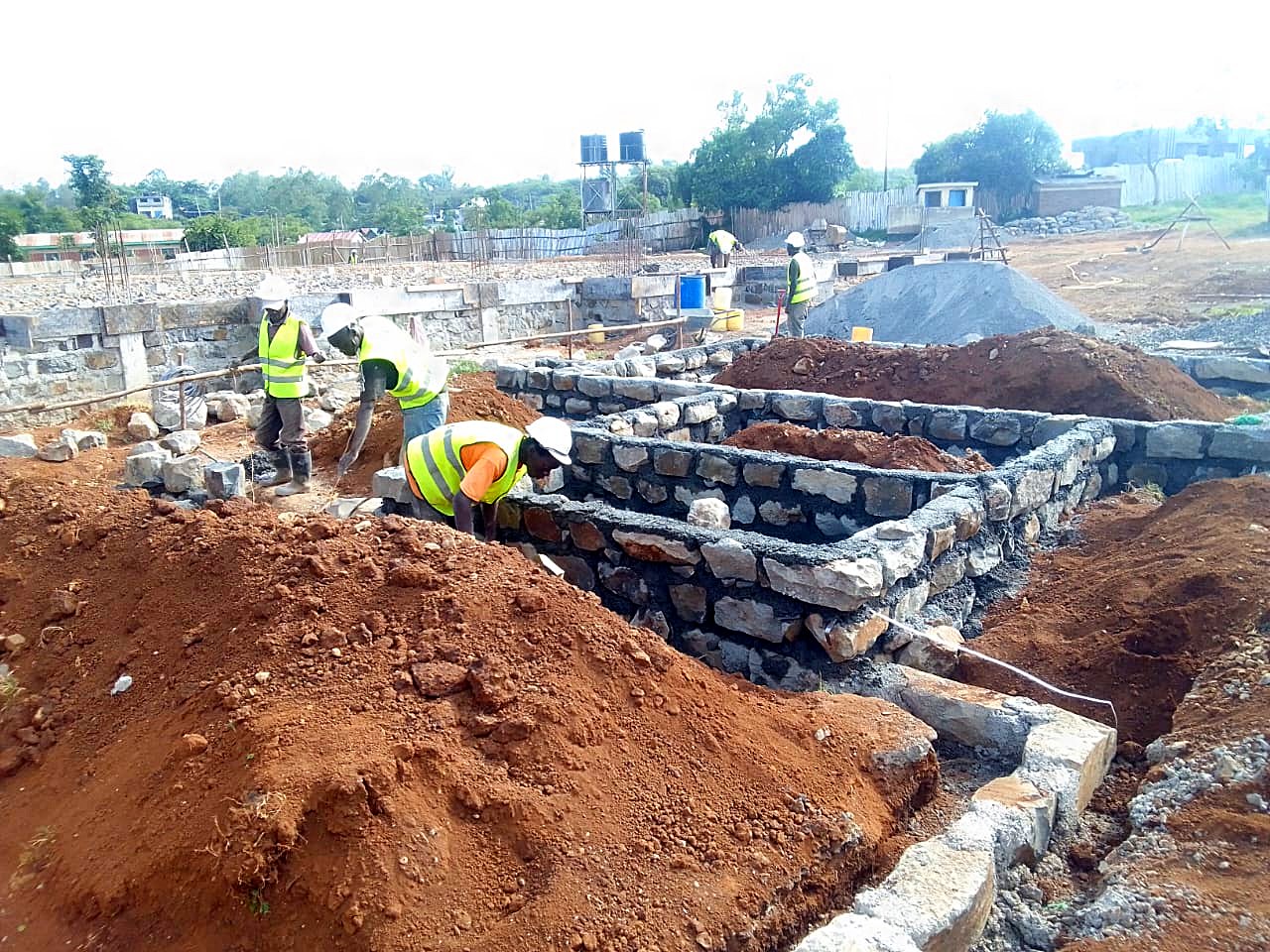 Site team in safety vests building stone masonry foundations
